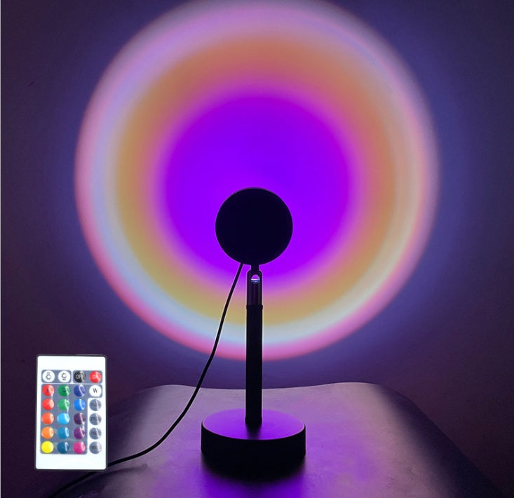Black lamp with remote control emitting colorful circular light patterns on a dark background